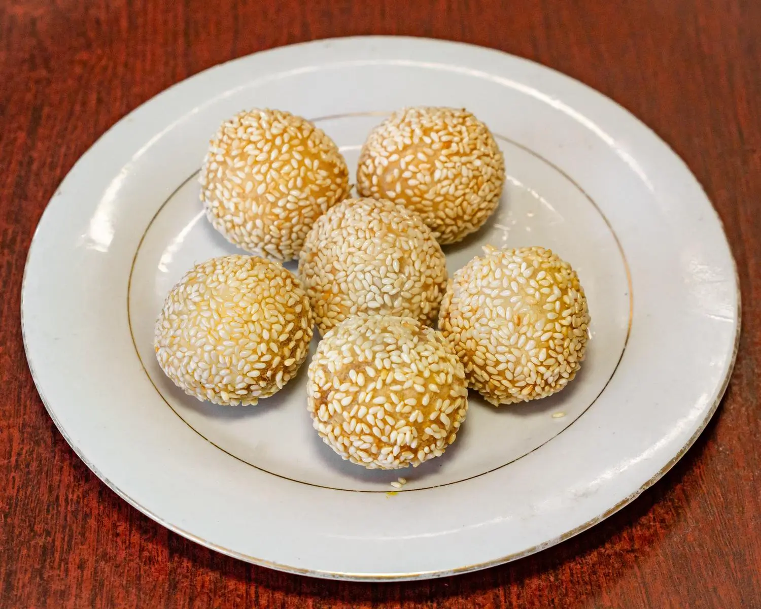 A plate of sesame balls, which are round, golden - brown balls coated with sesame seeds, placed on a white plate at Uncle Yu Restaurant，a Chinese Restaurant in Union City